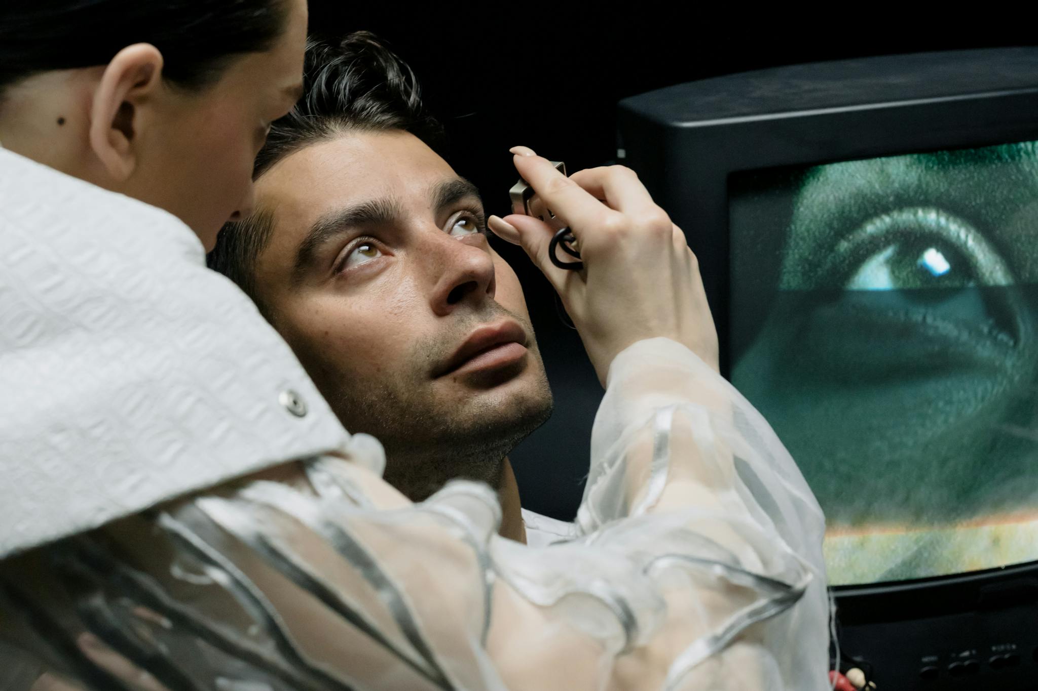 Close-up of a man having an eye examination with a monitor in the background.